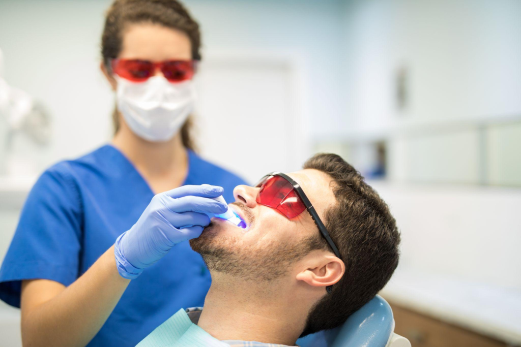 A female dentist offering laser teeth whitening to a man with laser protection glasses