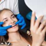 A woman smiling in the mirror as the dentist completes the veneer treatment