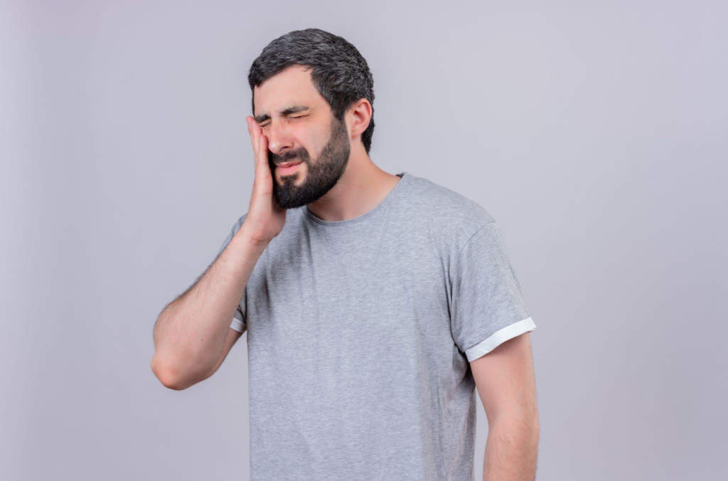 A man holding his jaw tightly because of the pain