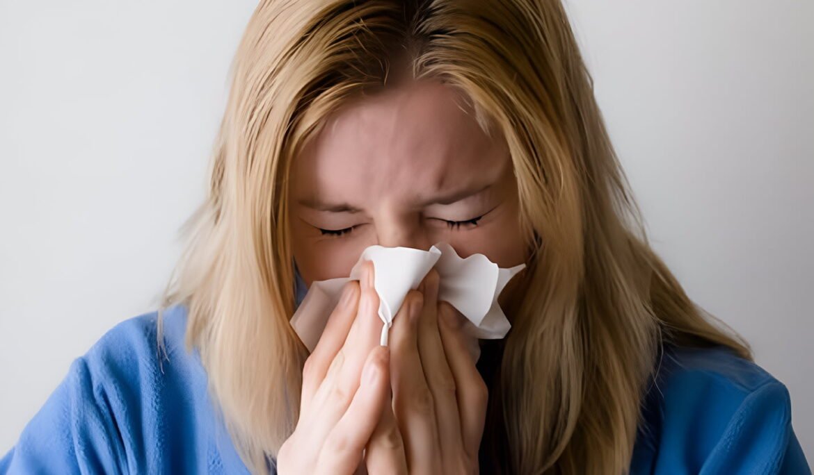 Woman sneezing into tissue suffering from seasonal allergy symptoms