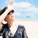 Beautiful lady on beach shielding herself from sunlight