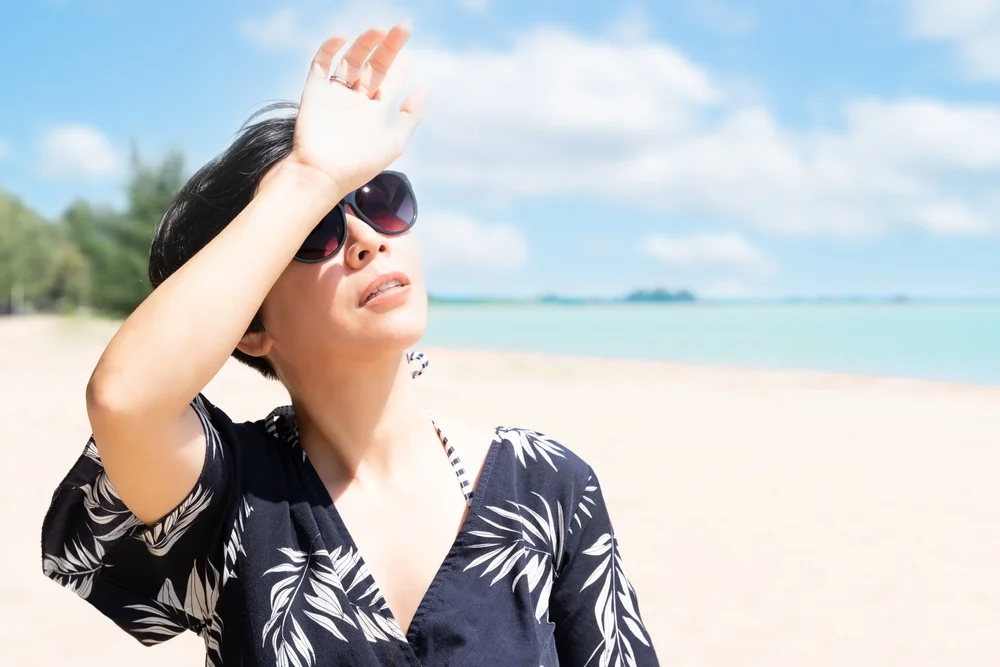 Beautiful lady on beach shielding herself from sunlight