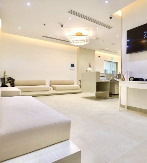 Modern dental clinic reception area with beige sofas and bright lighting.